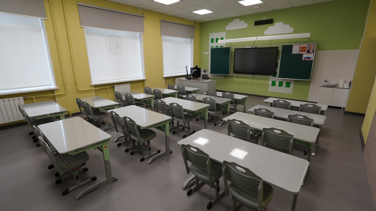 Классная комната — зелёные парты, интерактивная доска, герб школы 32